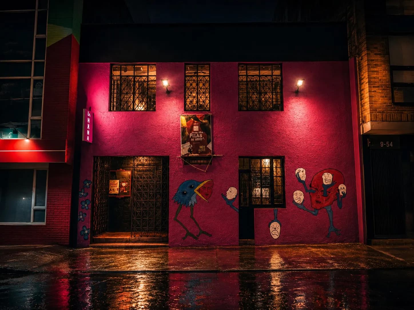 Fachada de Teatro La Mama de noche, bajo la lluvia