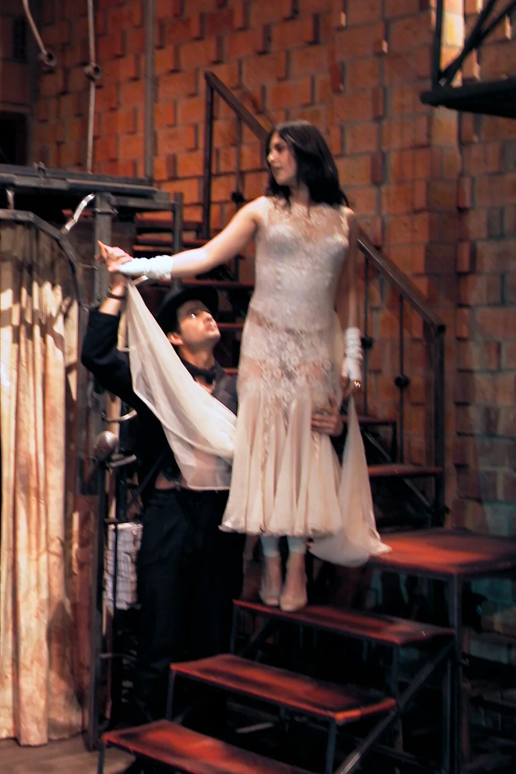 Personaje con vestido blanco en escaleras en Las impurezas del amor