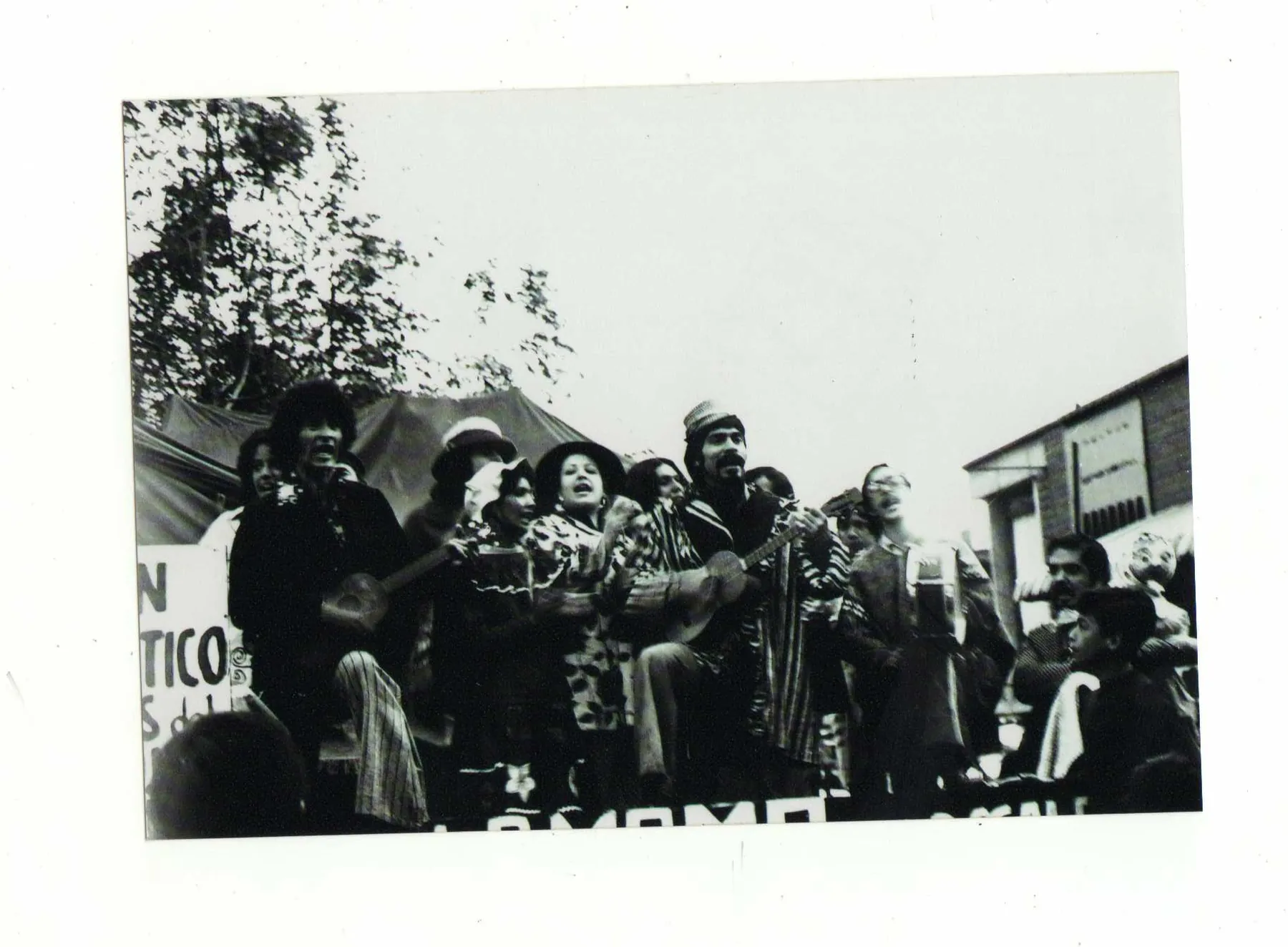Grupo de actores de La Mama con pancartas bajo una carpa en la calle