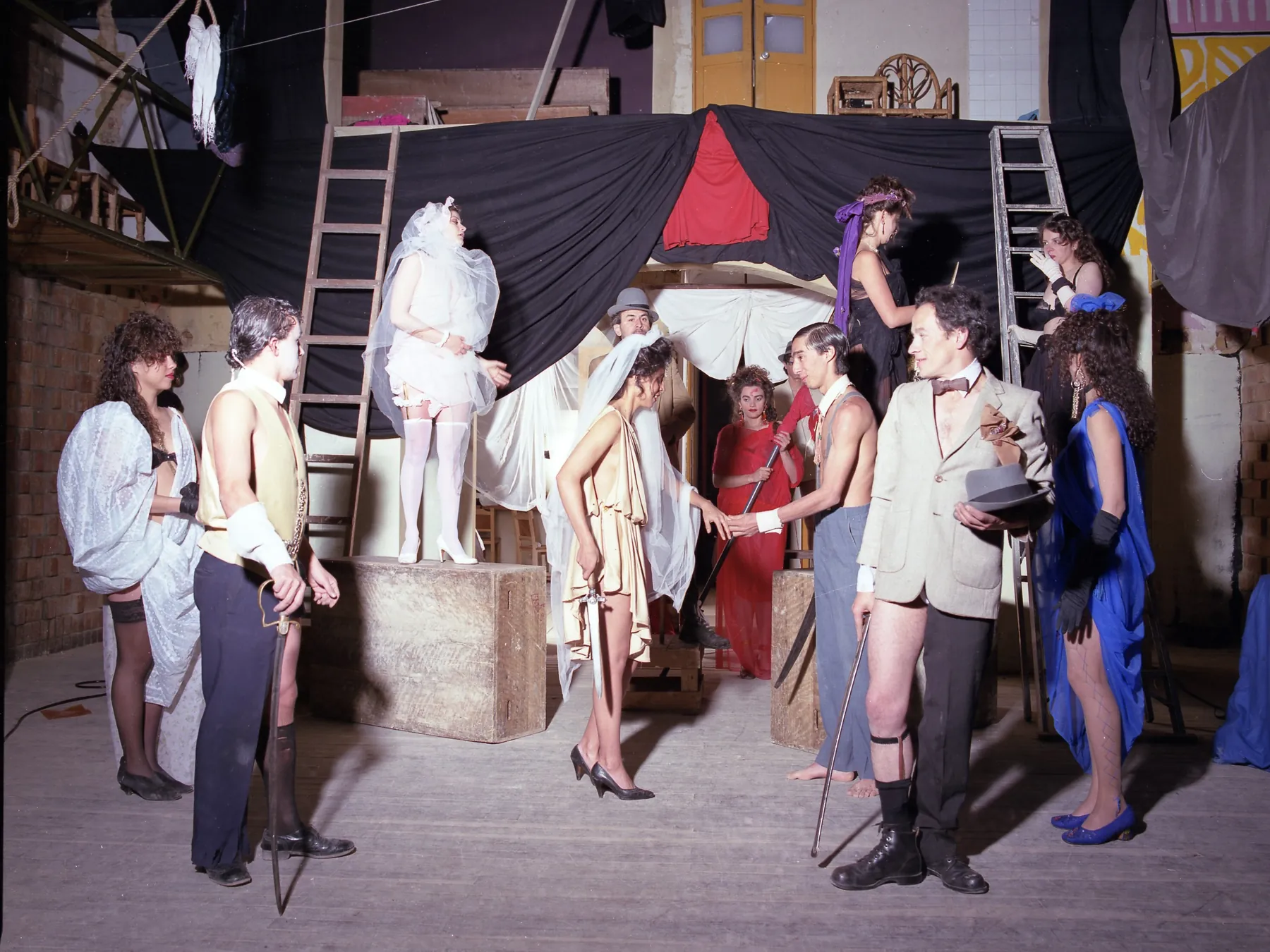 Elenco de La incertidumbre del amor en escena bajo una carpa de lona y escaleras